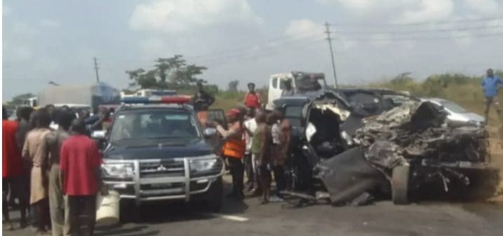 Accident scene with damaged vehicle, police, and crowd on the roadside.