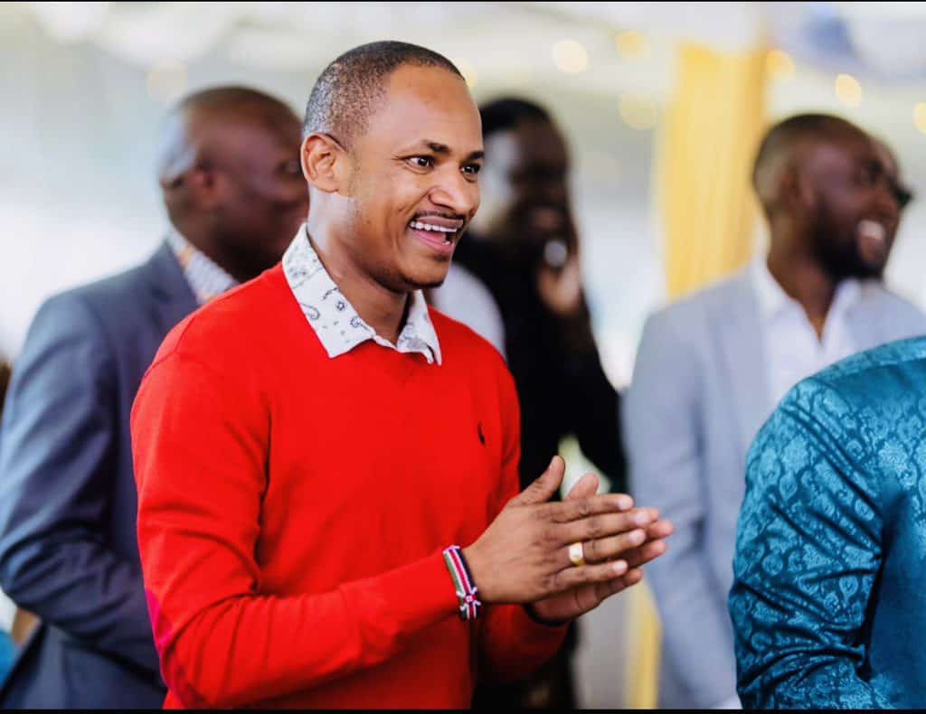 A smiling man in a red sweater at KWETU NEWS event, engaging with attendees and celebrating achievem.