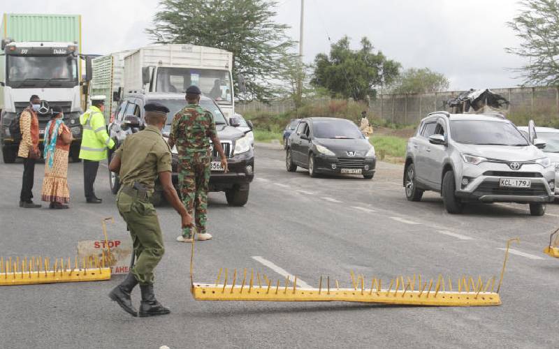 Kenyan police and military officers conduct vehicle inspection at a checkpoint.
