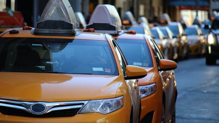 Yellow taxis lined up on a city street, ready for passengers.