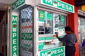 ATM cash withdrawal at M-PESA agent in Kenya, showing mobile money services and financial transactio.