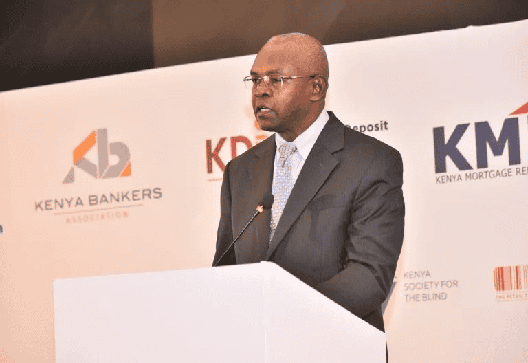 A man in a suit speaking at a Kenya Bankers Association event.