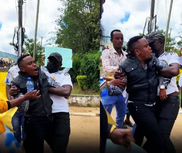 Community members protesting with a woman holding a child in an outdoor setting.