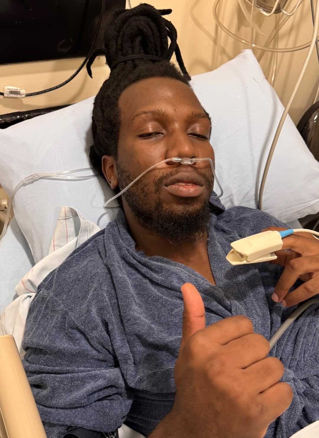Patient in hospital bed giving a thumbs-up, showing recovery and positivity.