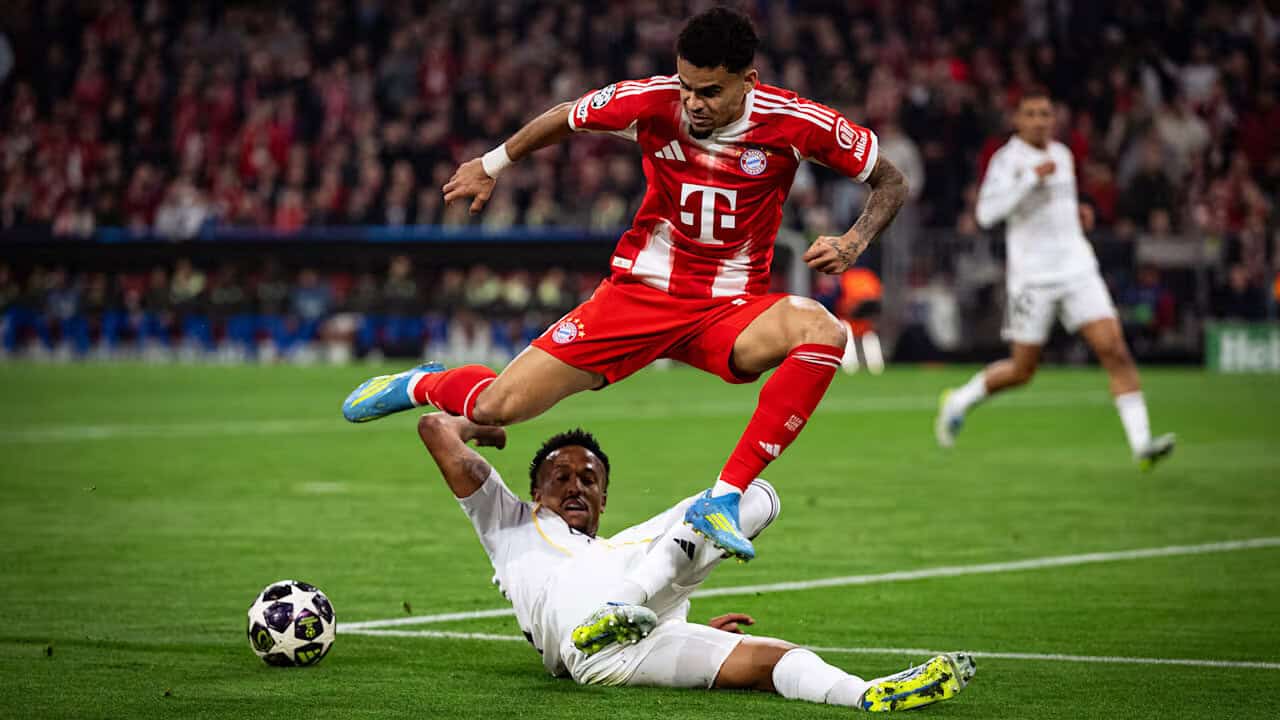 Football player in red jersey jumping over opponent on the field.