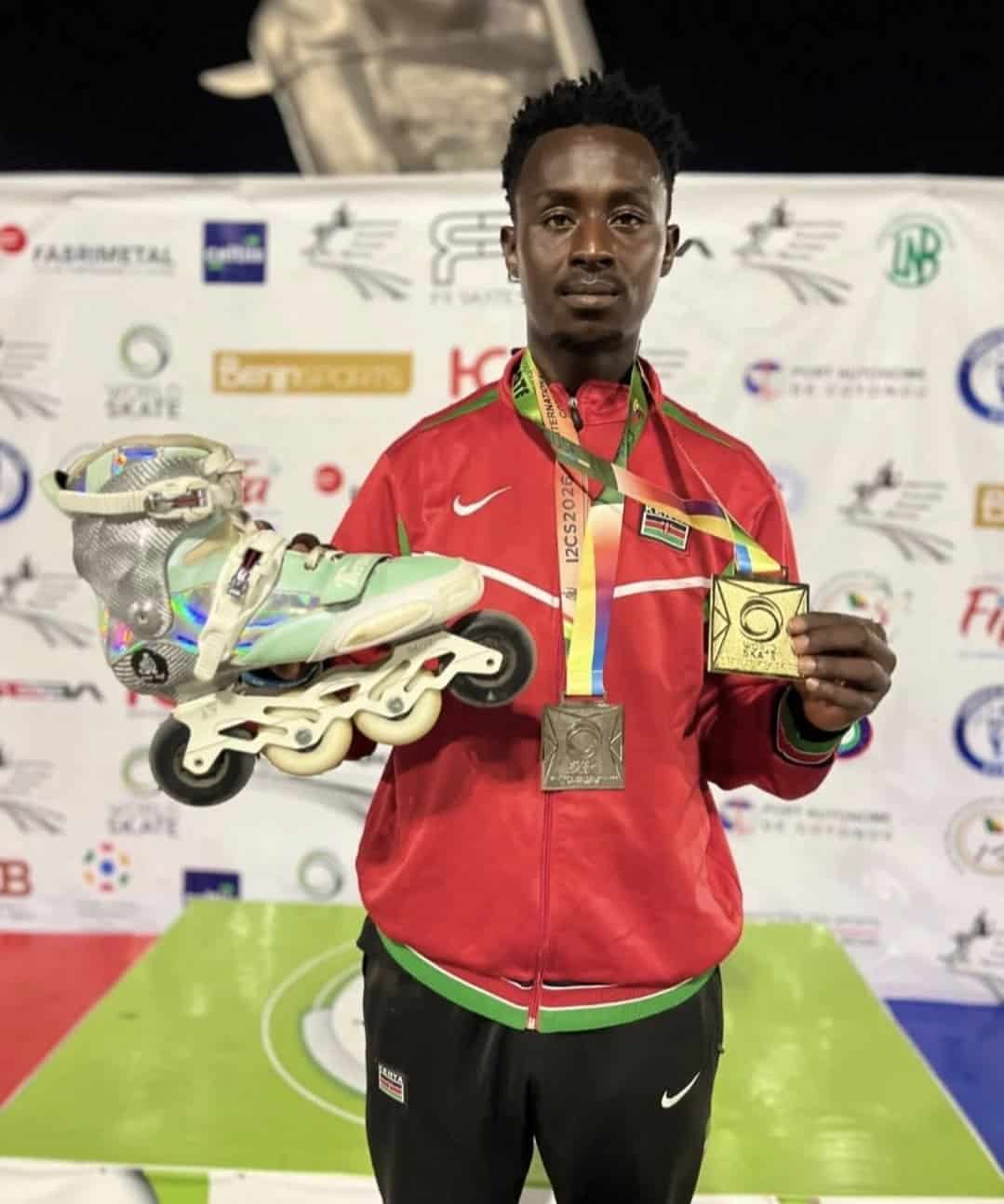 Kenyan athlete holding gold medal and inline skates at sports event.