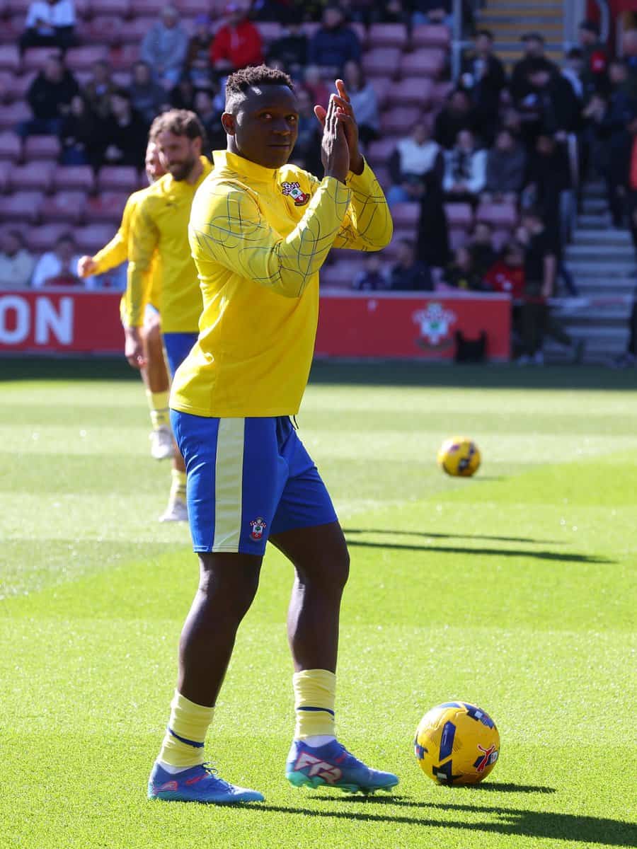 Kenyan football player in yellow jersey praying during match at Kwetuu Collections.